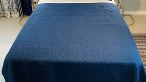 Una cama con cabecera de madera, dos mesitas de noche con lámparas, y un cartel que indica acceso a WiFi.
