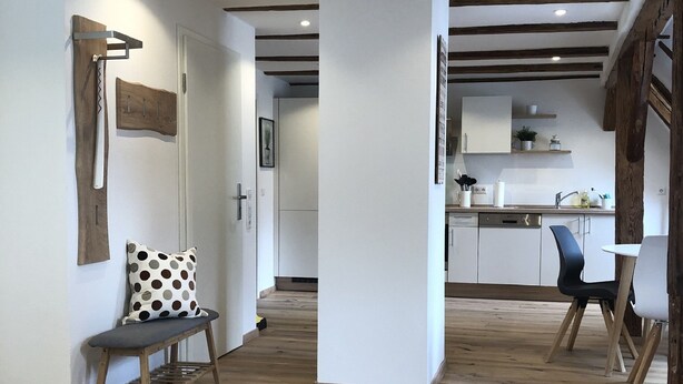 Une cuisine moderne avec des meubles blancs, un évier et un coin repas comprenant une table et des chaises.