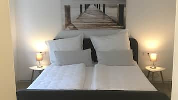 Ein Schlafzimmer mit einem Bett, zwei Nachttischen mit Lampen, einer Deckenleuchte und einem großen Wandbild, das einen Steg zeigt.