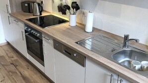 Une cuisine moderne dotée d’un plan de travail en bois, d’appareils électroménagers en acier inoxydable et de meubles blancs.