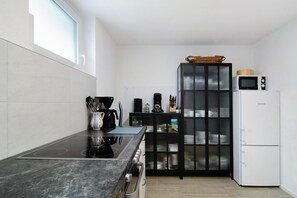 Moderni keittiö, jossa on musta työtaso, sisäänrakennettu liesi, mikroaaltouuni ja jääkaappi.