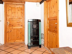 Features a traditional door and stove, along with a tiled floor and woven bench.