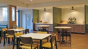 A restaurant with multiple tables and chairs, a kitchen area, and a counter.