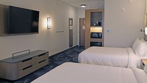 A hotel room with two beds, a flat-screen TV mounted on the wall, a minibar, and a wooden wardrobe.