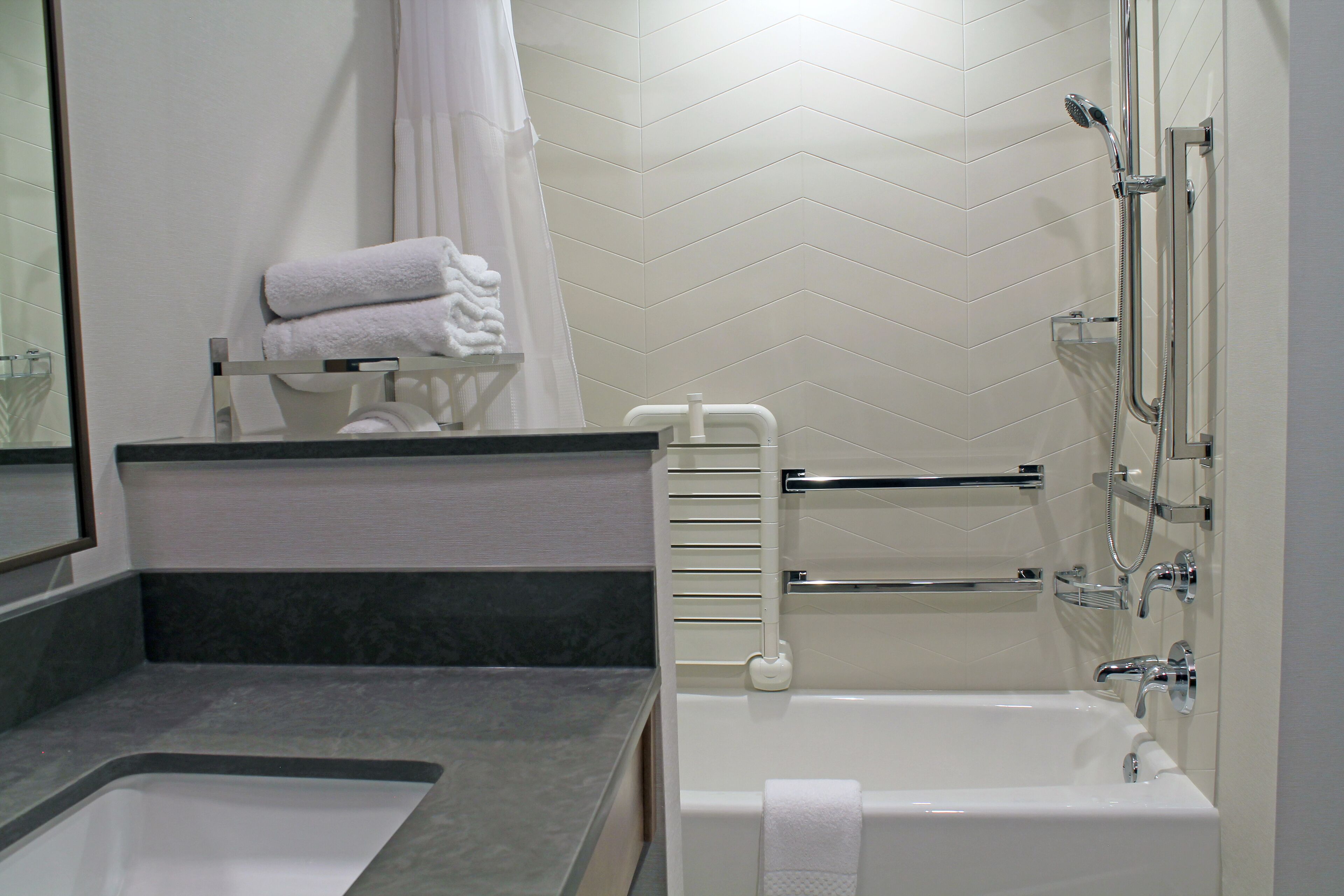 A modern bathroom with a bathtub, a shower, and a vanity with a sink.