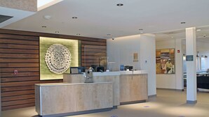 A reception area with a wooden wall and a large decorative piece. There are two reception counters and a sign on the wall.