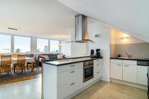 Eine moderne Küche mit Kochinsel, integriertem Backofen und Dunstabzugshaube aus Edelstahl.