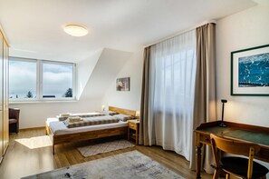 Un dormitorio con cama, mesita de noche, lámpara y escritorio con silla.