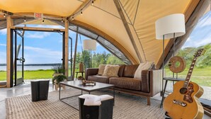 Een tent met een bank, een bijzettafeltje, een lamp en een gitaar.