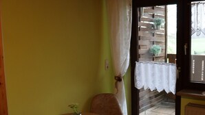 A cozy room with a wooden bench, two chairs, a small table with a vase, and a window with a view of the outside. - Gasthof Zur Altmühlquelle (Windelsbach)