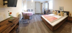Un dormitorio con cama, escritorio, silla, una mesita y televisor.