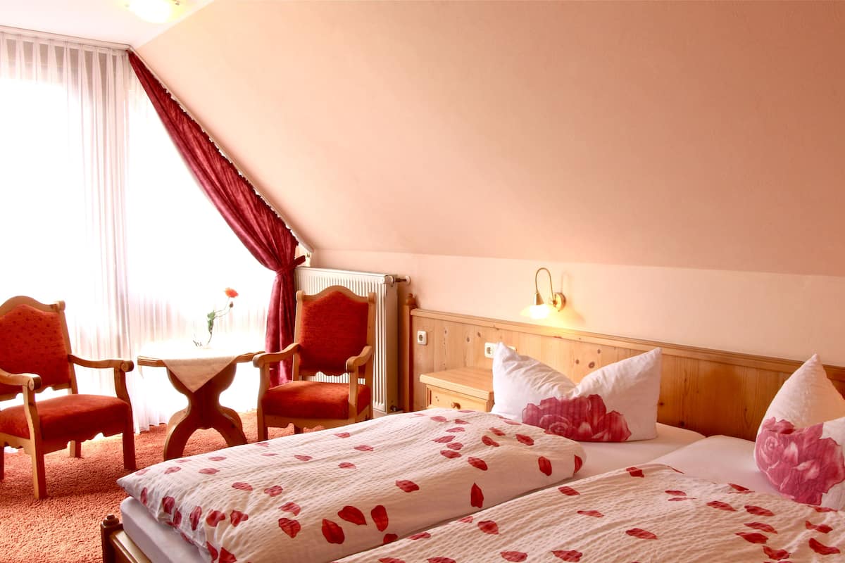 Una habitación de hotel con cama, dos sillas, una mesita y una mesita de noche.