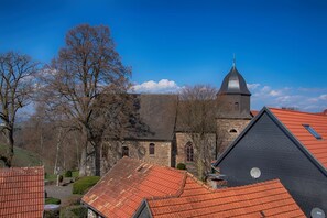 Una iglesia histórica con una torre destacada y un campanario, rodeada de edificios residenciales con tejados de tejas rojas.