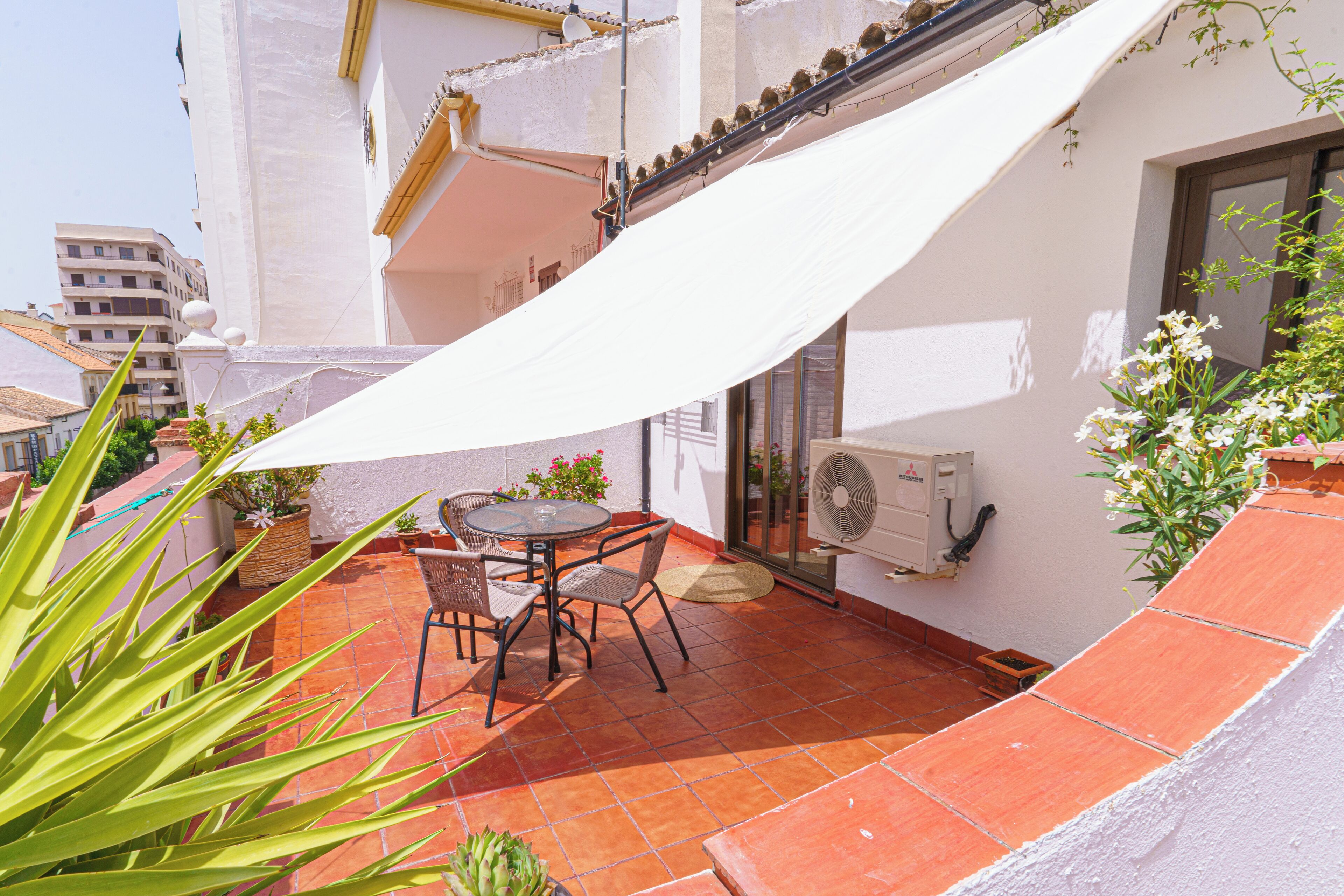A patio with a table and chairs, a white awning, and potted plants.