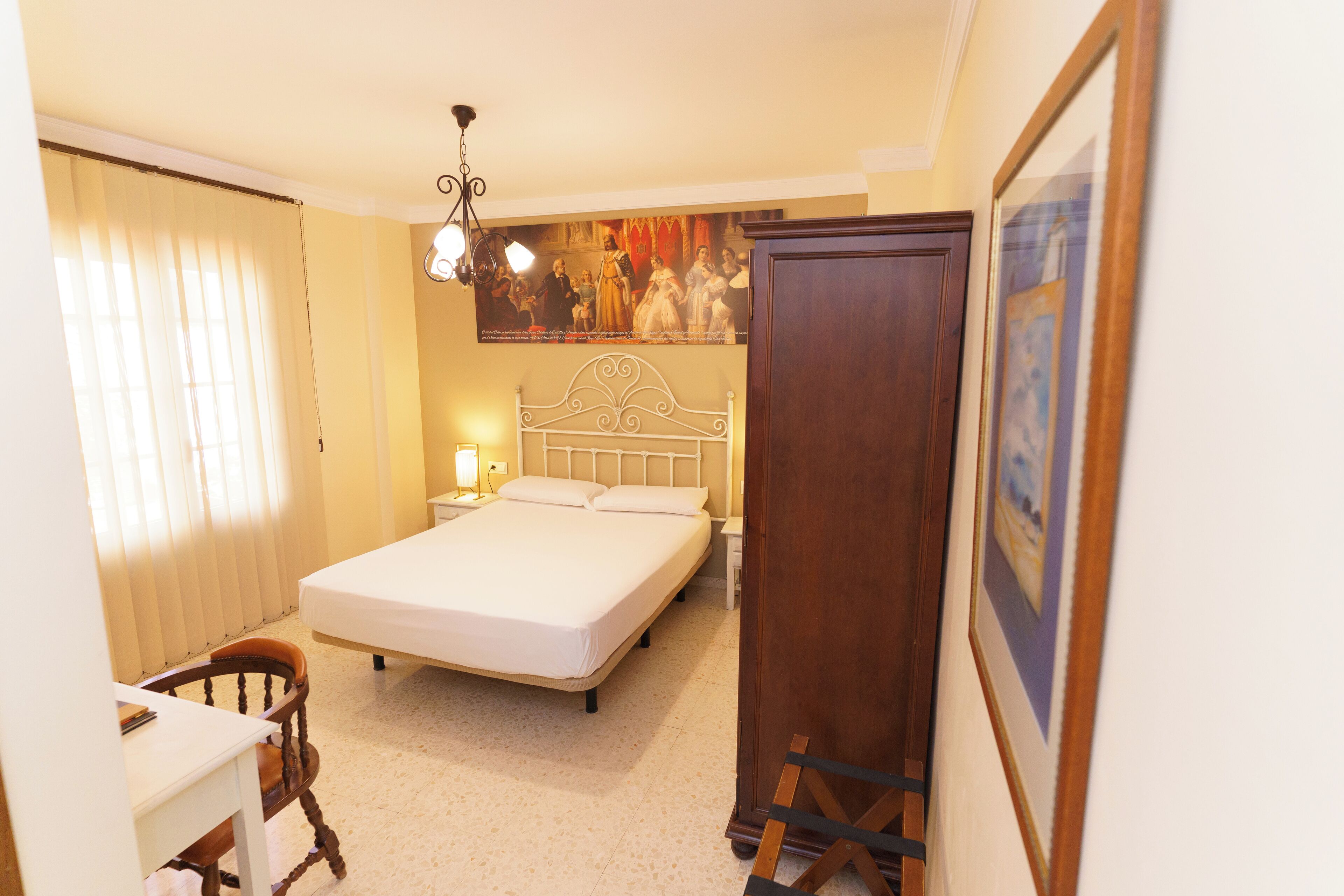 A bedroom with a bed, bedside tables, a chair, a desk, and a wardrobe.