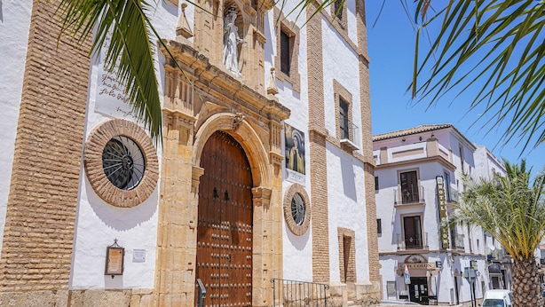 A historic building with a large wooden door, a clock, and a sign for 'Hotel Colon'. - Hotel Colón (Ronda)