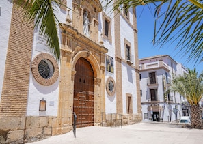 A historic building with a large wooden door, a clock, and a sign for 'Hotel Colon'. - Hotel Colón (Ronda)