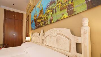 Una habitación de hotel con una cama grande, un armario de madera y un cuadro colgado en la pared.