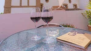 A round table with two wine glasses and a book, set against a backdrop of a building with a bell tower. - Hotel Colón (Ronda)