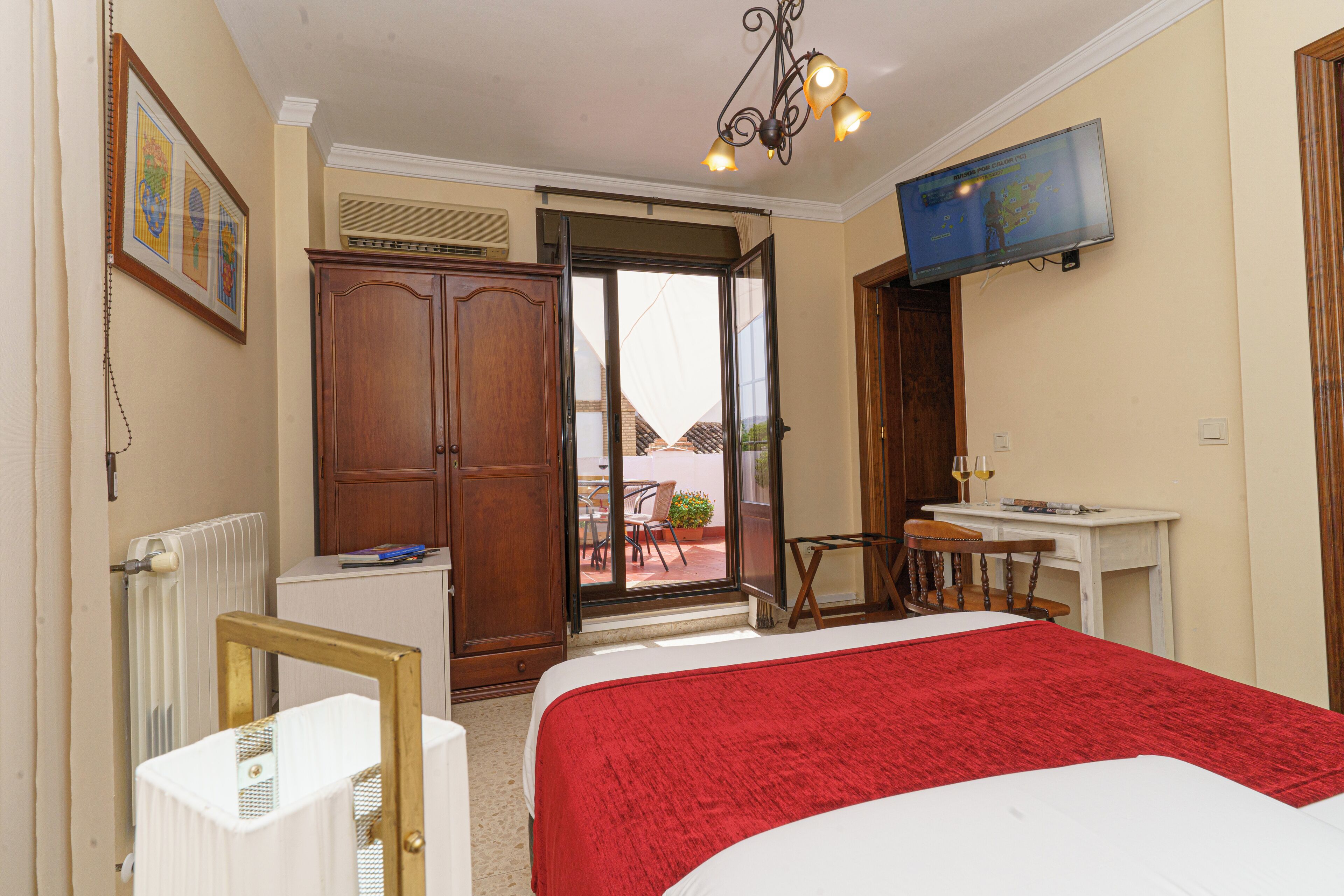 Habitación de hotel con cama, escritorio, silla, televisión y vista al exterior.