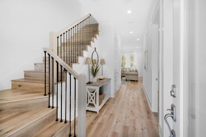 Staircase leads to a landing area with a console table and a potted plant.