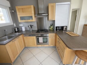 A kitchen with wooden cabinets, a stainless steel sink, a stove, and a toaster.