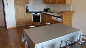 Une cuisine compacte avec des meubles en bois, un four encastré, un évier et une table à manger avec des chaises.