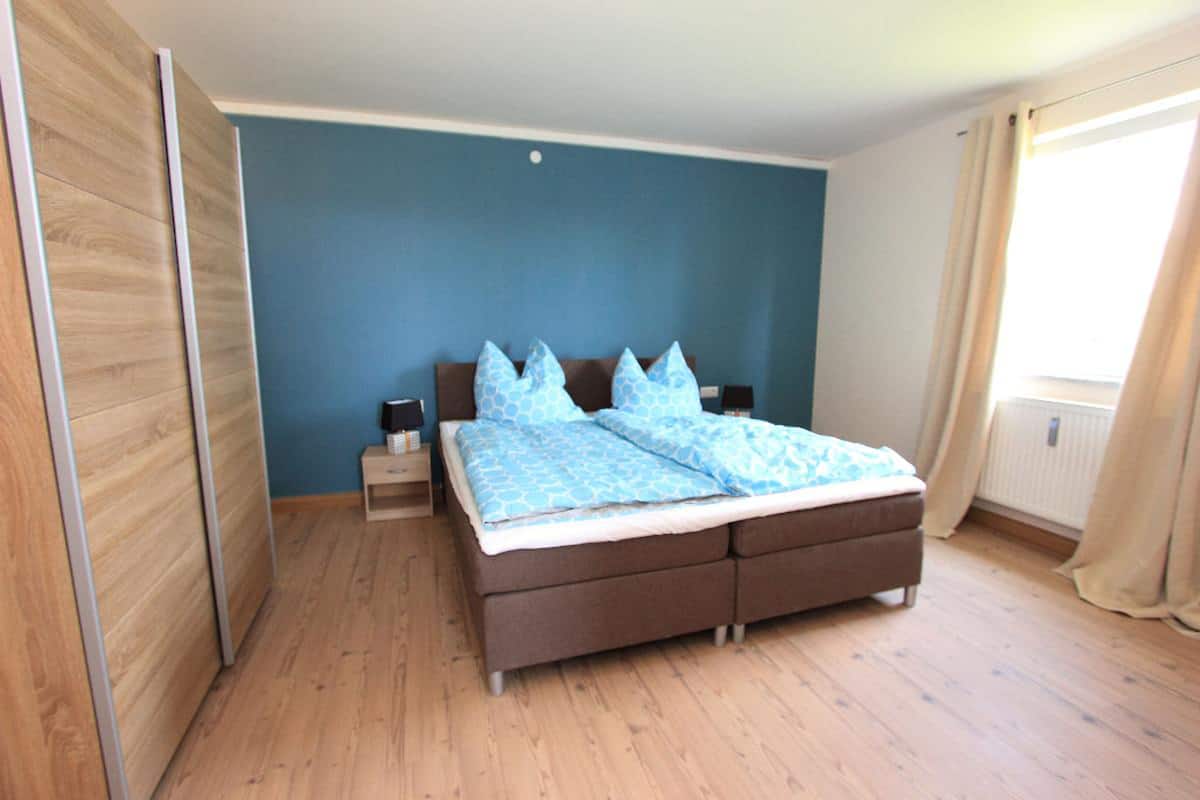 A bedroom with a bed, a nightstand, and a wardrobe.