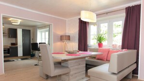 Una sala de estar moderna con una mesa de comedor, dos sofás y un ventanal con cortinas.