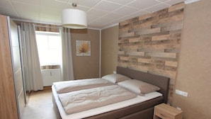 Un dormitorio con una cama doble, una mesita de noche y un panel de madera decorativo en la pared.