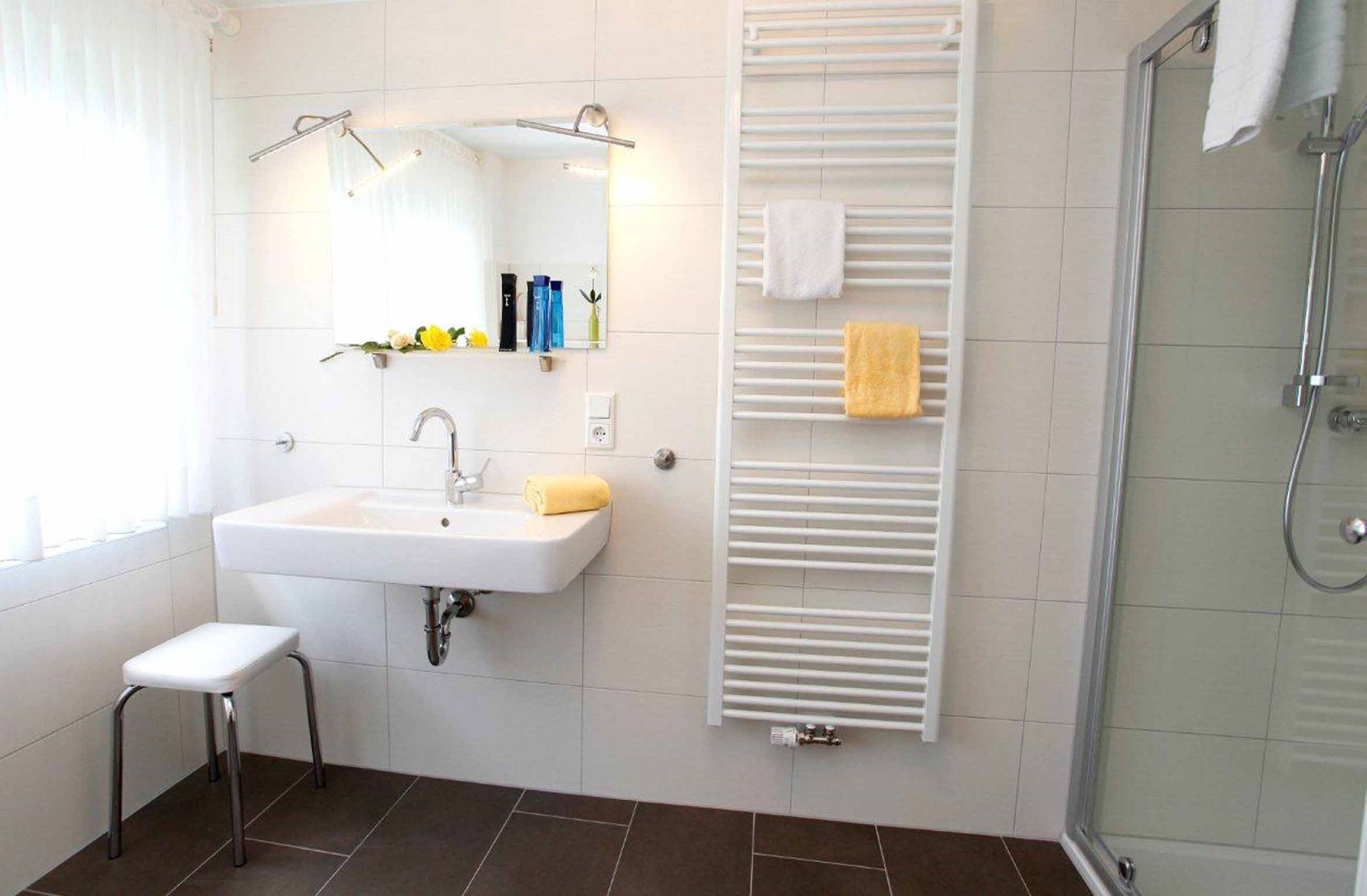 A modern bathroom with a white sink, mirror, and towel rack.