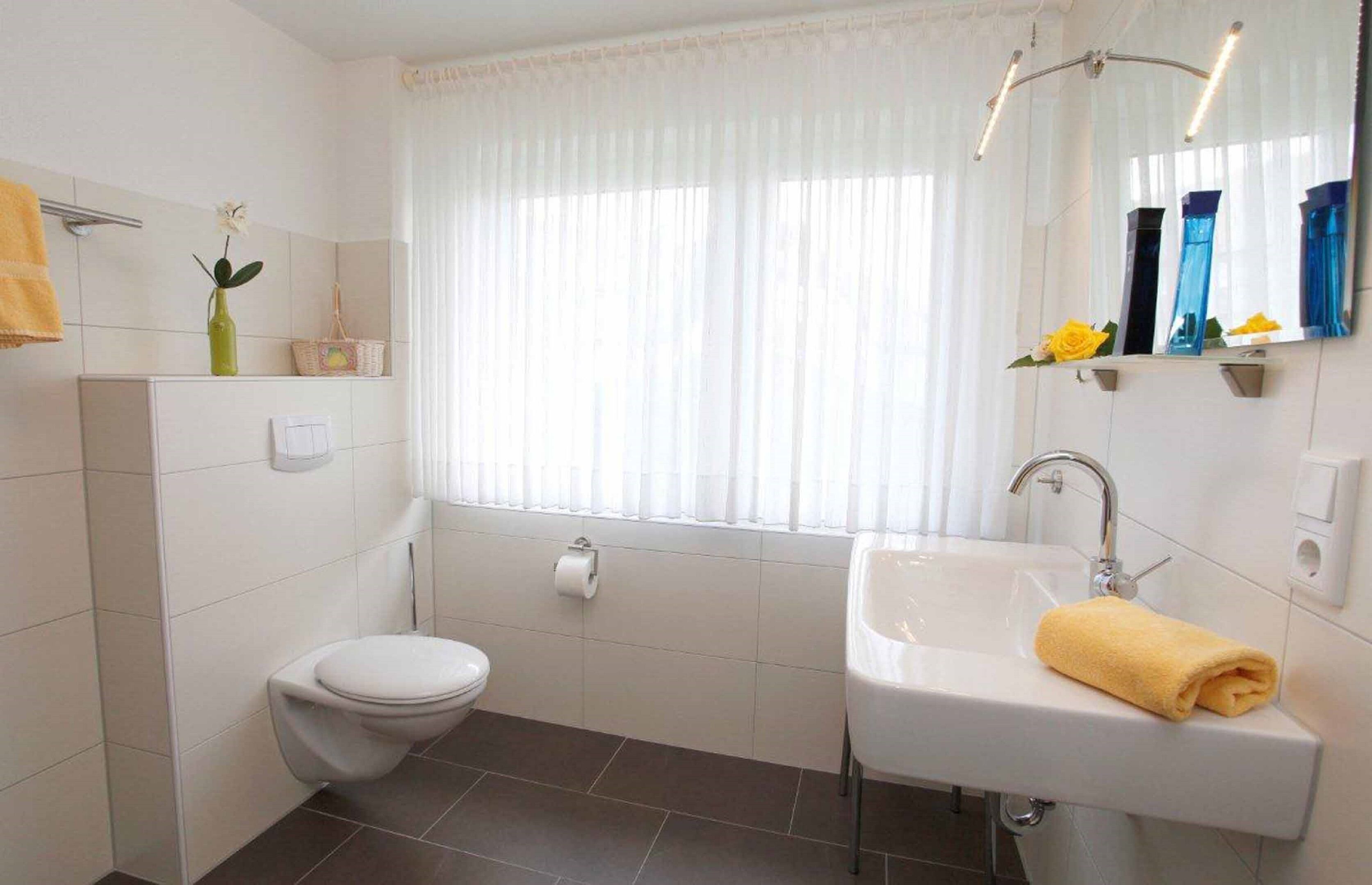 Et moderne badeværelse med toilet, håndvask og vindue.