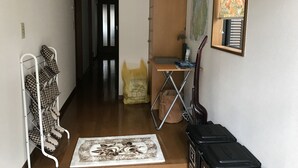 Un passadís amb un prestatge de sabates, un escriptori amb un mapa, una guitarra i una bossa amb queviures.