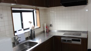 Una cuina amb rajoles blanques, electrodomèstics d'acer inoxidable i armaris de fusta.