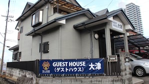 Edifici de dues plantes amb un cartell que diu "GUEST HOUSE" i "大津", indicant-ne la ubicació.