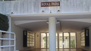 En byggnadsentré med skylten ”ROYAL PARK”, en stor pelare, glasdörrar och ett metallräcke.