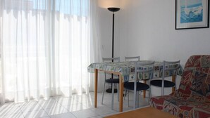 Ett vardagsrum med ett matbord, stolar, en soffa och en golvlampa.