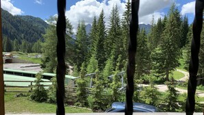 Une vue à travers une fenêtre à cadre en bois, donnant sur une zone boisée avec une montagne en arrière-plan.