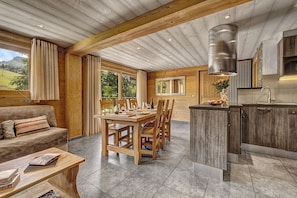 A wooden interior with a dining area, kitchen, and a view of the outdoors. - Luxury flat with a mountain feel (Le Grand-Bornand)