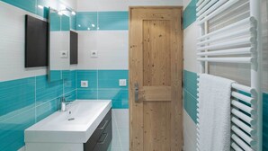A bathroom with a wooden door, a white sink, and a towel rack.