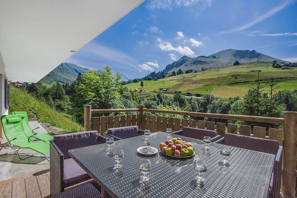 Mesa lista para comer con vista a la montaña, asientos al aire libre y una terraza de madera.