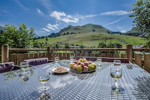 An outdoor dining table with a view of a green hill and a mountain in the distance. - Luxury flat with a mountain feel (Le Grand-Bornand)