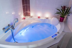 Ein modernes Badezimmer mit freistehender Badewanne, einer Handbrause und einem Blumentopf.