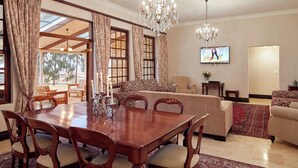 A dining area with a wooden table and chairs, a sofa, and a television. - Dog-friendly Farm Cottage in the Berg by First Private Stays (Drakensberg Gardens)