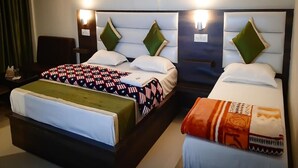 Habitación de hotel con dos camas, cada una con cabecera, mesita de noche y lámpara.