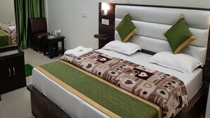 Una habitación de hotel ordenada con una cama grande, una mesita de noche, una silla y un aparador.