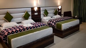 Una habitación de hotel con dos camas, cada una con cabecera y almohadas.