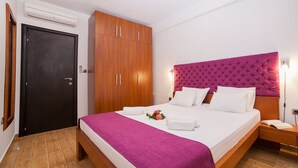 A hotel room with a bed, a wardrobe, a door, and a nightstand.