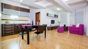 A modern living room with a dining area, wooden flooring, a sofa, and a TV.