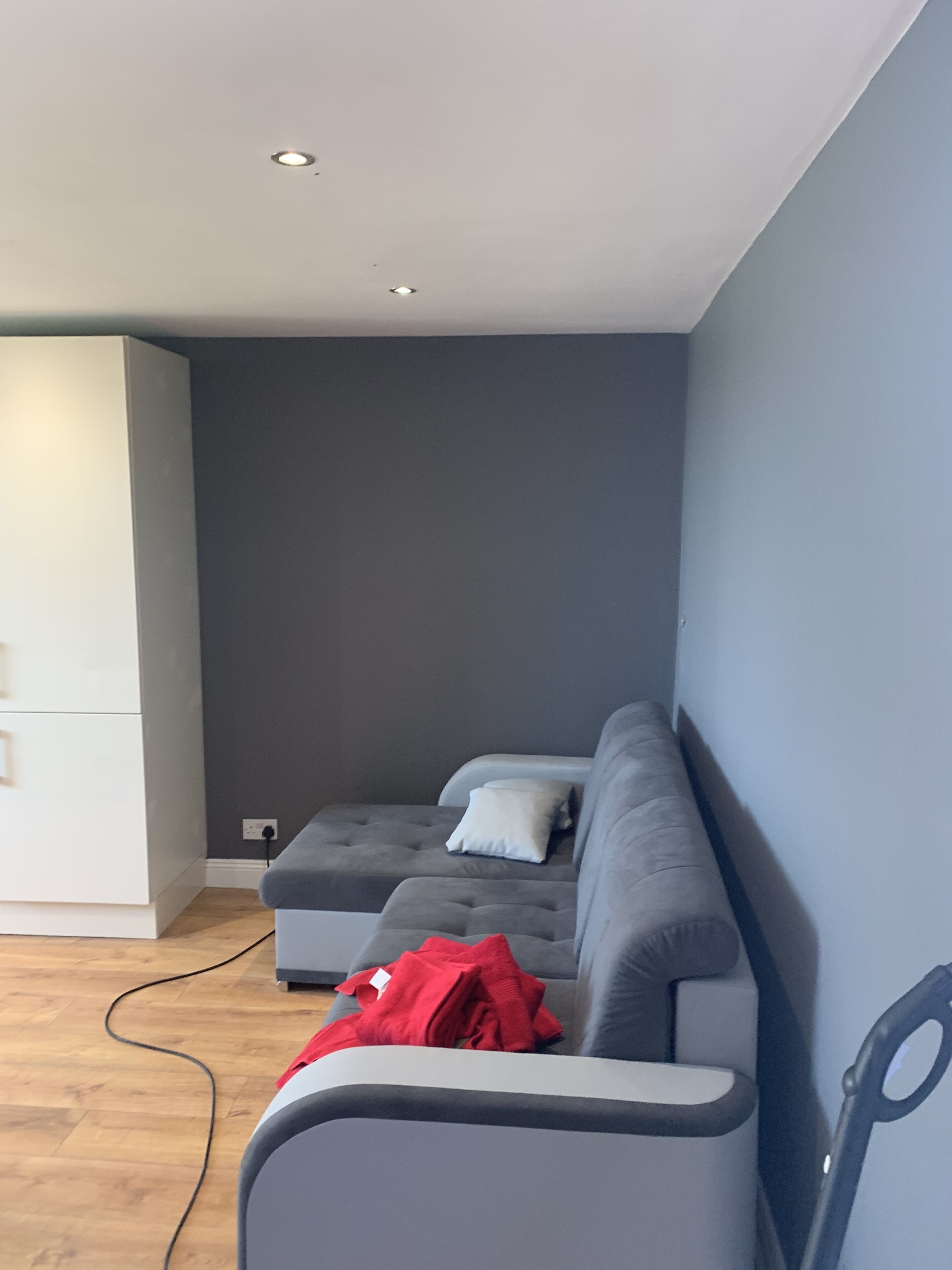 A modern living room with a grey sofa, a white cabinet, and a wooden floor.